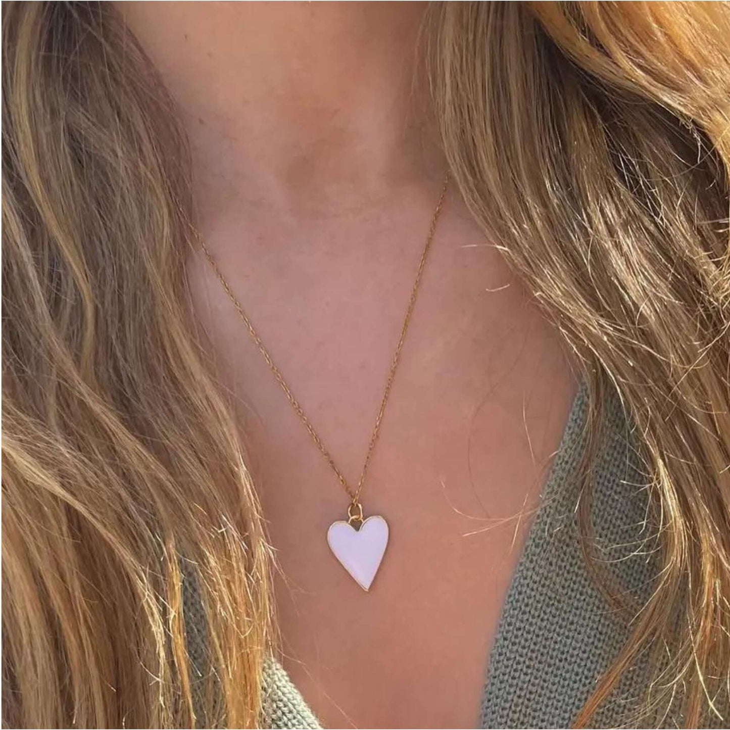 Claire White and Gold Heart Pendant Necklace worn by a person, showcasing its elegant white and gold heart design.