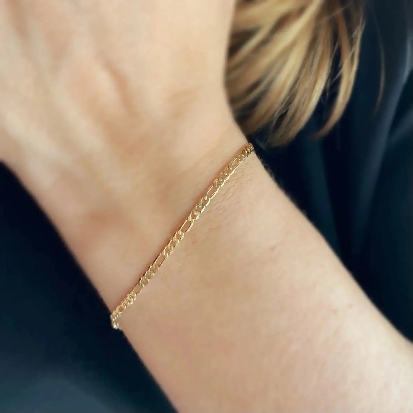 Flora 18K Gold-Filled Flat Figaro Chain Bracelet worn on a wrist, showcasing its elegant design and shine.