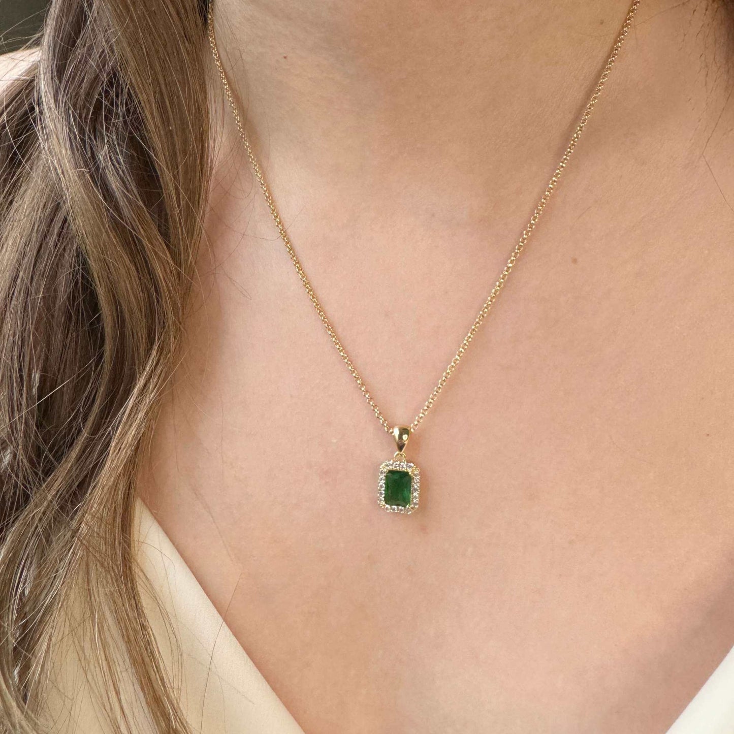 Holly Emerald Green CZ Pendant Gold Necklace worn on a person's neck, featuring a cushion-cut emerald green cubic zirconia.