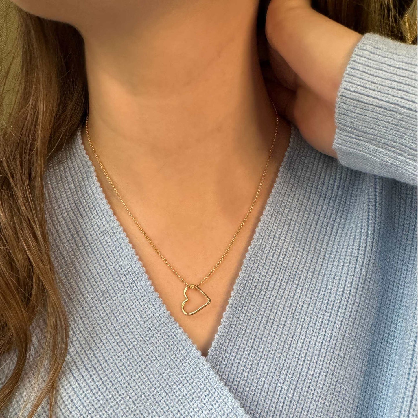 Isabella Gold Filled Open Heart Charm Necklace worn on a model's neck, showcasing its elegant design.