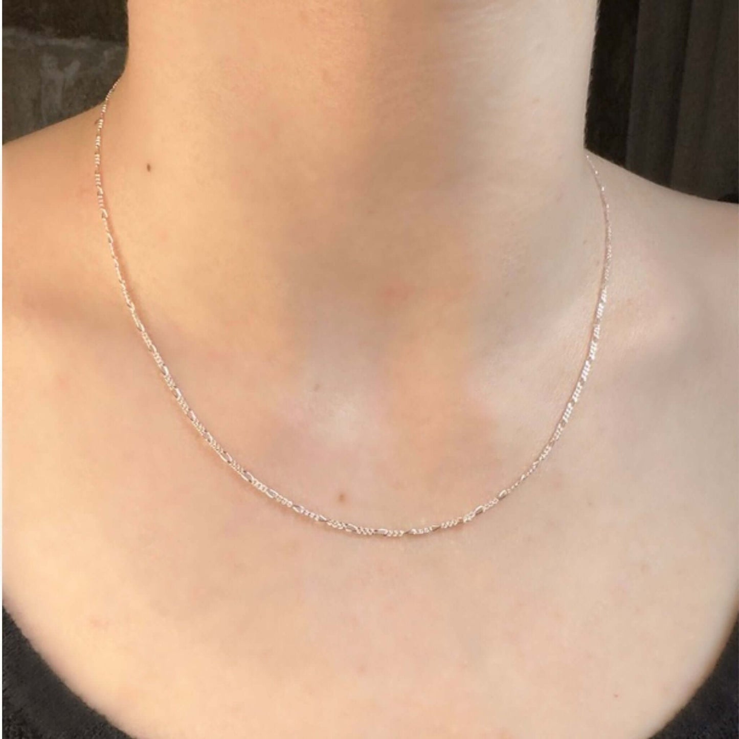 Quinn Sterling Silver Figaro Chain Necklace worn on a neck, showcasing its elegant design and alternating link pattern.